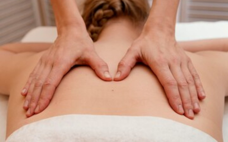 Licensed massage therapist at Uniq Massage in McKinney TX performing a Swedish massage for a relaxed guest